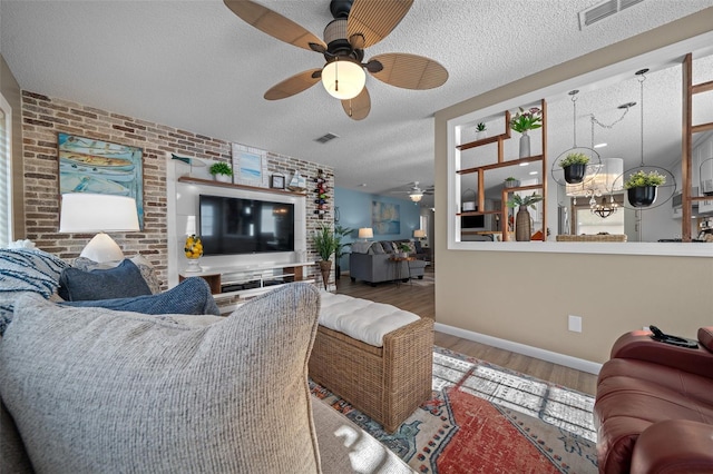 living room with visible vents, a textured ceiling, brick wall, and wood finished floors