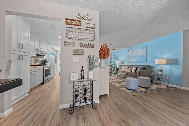 living area with a textured ceiling, baseboards, and light wood-style floors