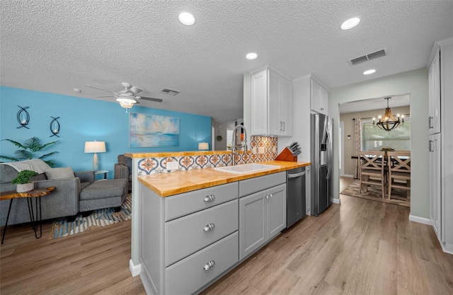 kitchen with butcher block countertops, a sink, visible vents, open floor plan, and appliances with stainless steel finishes