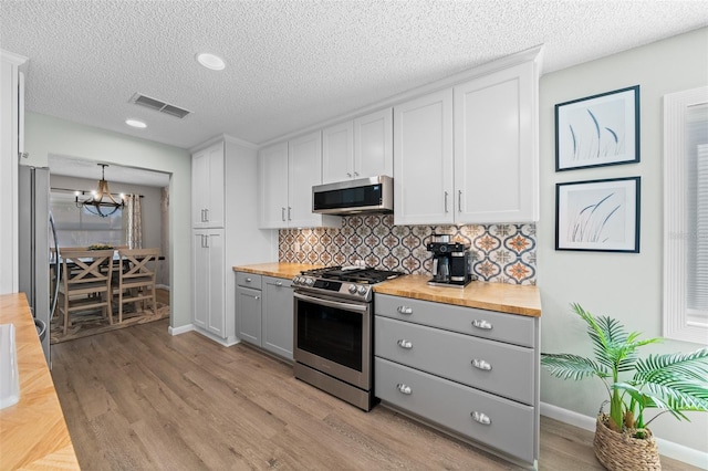 kitchen with stainless steel appliances, butcher block counters, visible vents, backsplash, and gray cabinetry