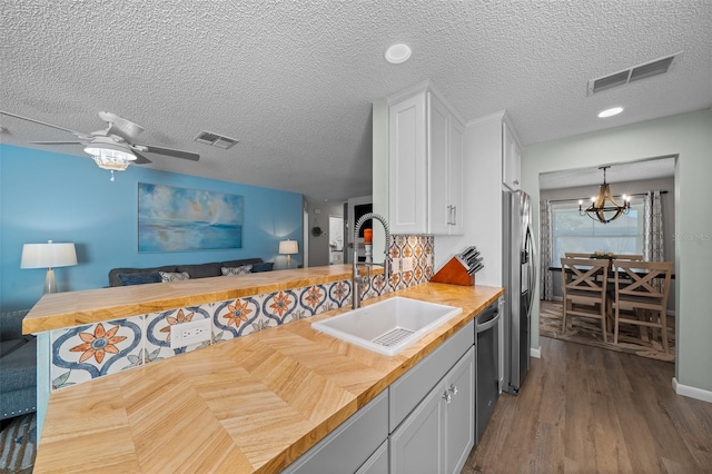 kitchen with butcher block countertops, a sink, visible vents, open floor plan, and appliances with stainless steel finishes