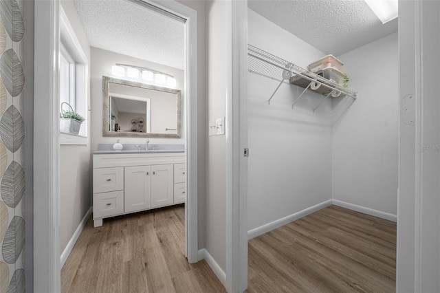 walk in closet with light wood-style floors and a sink