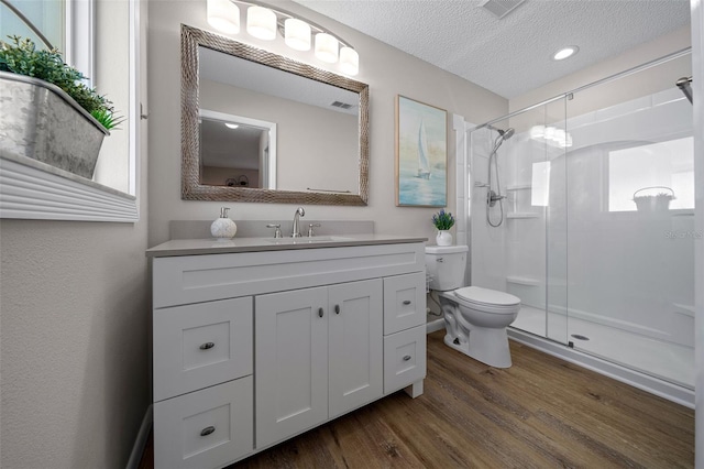 full bath featuring a stall shower, a textured ceiling, toilet, and wood finished floors