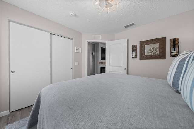 bedroom with a closet, visible vents, a fireplace, and a textured ceiling