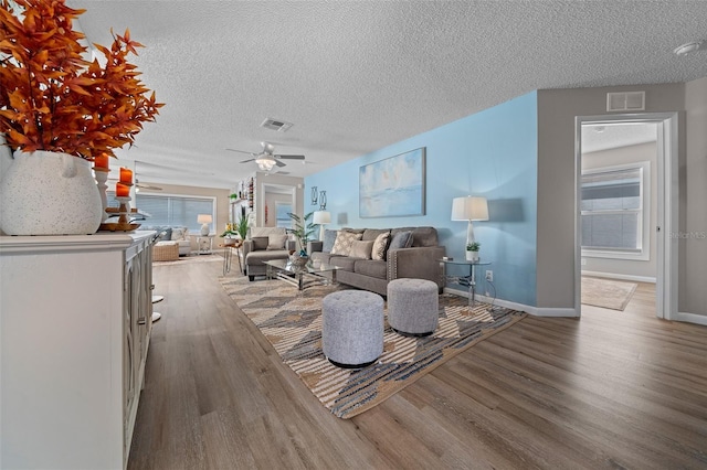 unfurnished living room featuring baseboards, a textured ceiling, visible vents, and wood finished floors