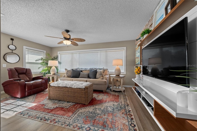 living room featuring ceiling fan, a textured ceiling, wood finished floors, and baseboards