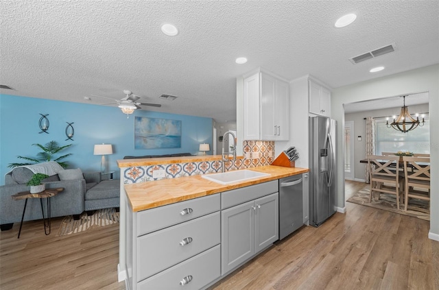 kitchen featuring visible vents, appliances with stainless steel finishes, open floor plan, wooden counters, and a sink