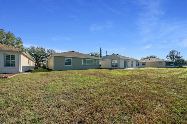 back of property with a lawn and stucco siding