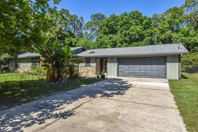 ranch-style home with a shingled roof, concrete driveway, an attached garage, fence, and a front yard