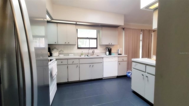 kitchen featuring light countertops, decorative backsplash, white cabinetry, a sink, and white appliances