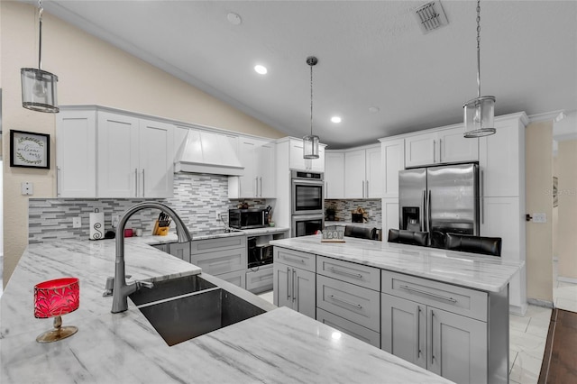 kitchen with visible vents, appliances with stainless steel finishes, vaulted ceiling, premium range hood, and a sink