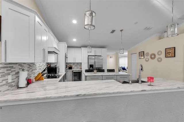 kitchen featuring visible vents, a kitchen island, wine cooler, stainless steel refrigerator with ice dispenser, and a sink