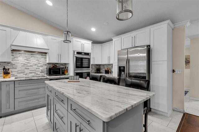 kitchen featuring lofted ceiling, a kitchen island, marble finish floor, light stone countertops, and black appliances