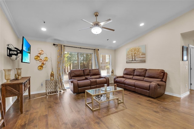 living area featuring hardwood / wood-style flooring, a ceiling fan, baseboards, vaulted ceiling, and crown molding