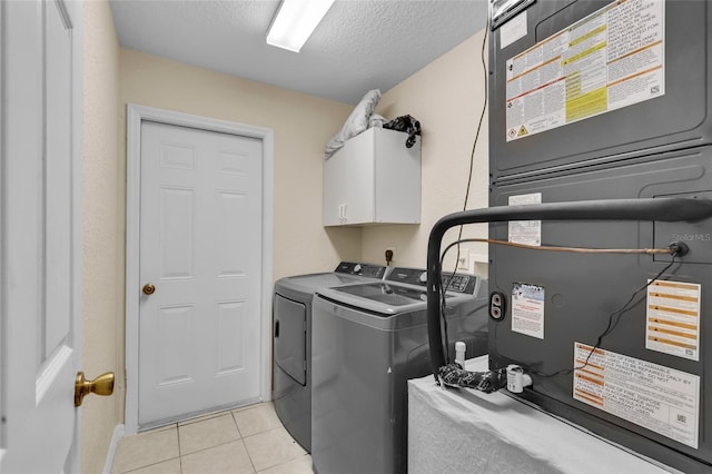 washroom featuring heating unit, light tile patterned floors, cabinet space, a textured ceiling, and independent washer and dryer