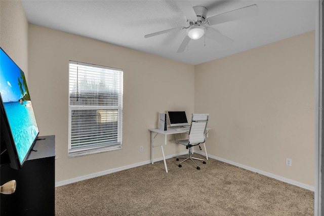carpeted office space with a ceiling fan and baseboards