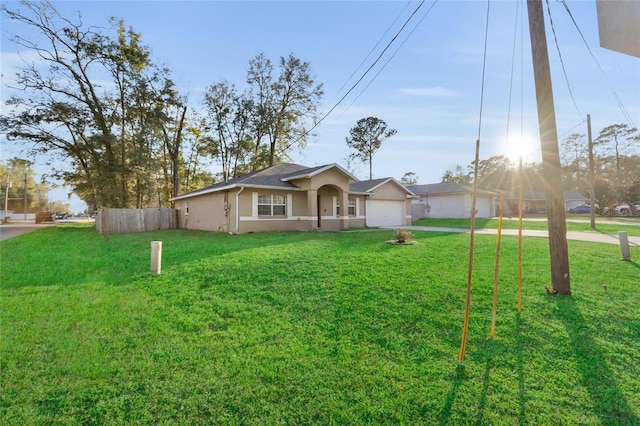 view of front of house featuring driveway, an attached garage, fence, a front yard, and stucco siding
