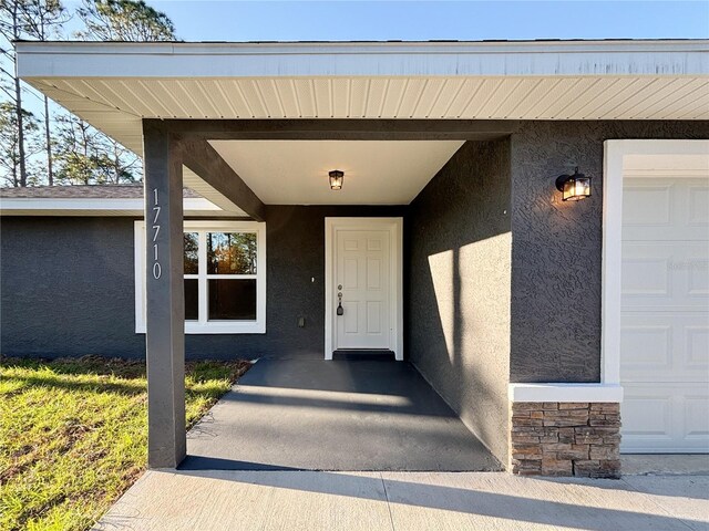 view of exterior entry featuring stone siding and stucco siding