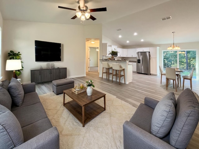 living room with light wood finished floors, visible vents, ceiling fan with notable chandelier, vaulted ceiling, and recessed lighting