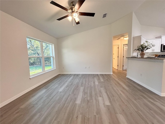 unfurnished living room with lofted ceiling, ceiling fan, visible vents, baseboards, and light wood-style floors