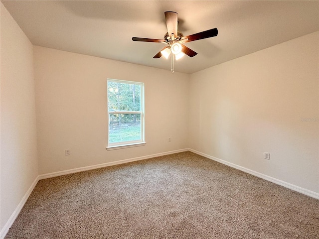 empty room with carpet flooring, a ceiling fan, and baseboards