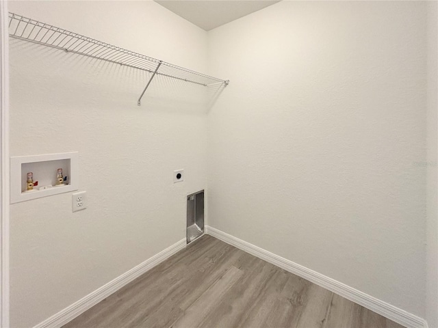 clothes washing area featuring laundry area, baseboards, hookup for a washing machine, light wood-style floors, and electric dryer hookup