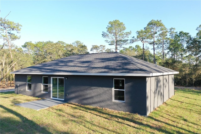 back of property with roof with shingles and a yard