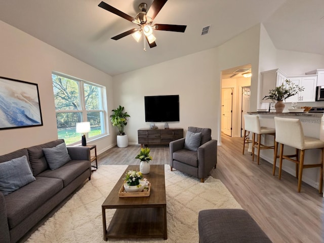 living room with lofted ceiling, ceiling fan, visible vents, and light wood-style floors