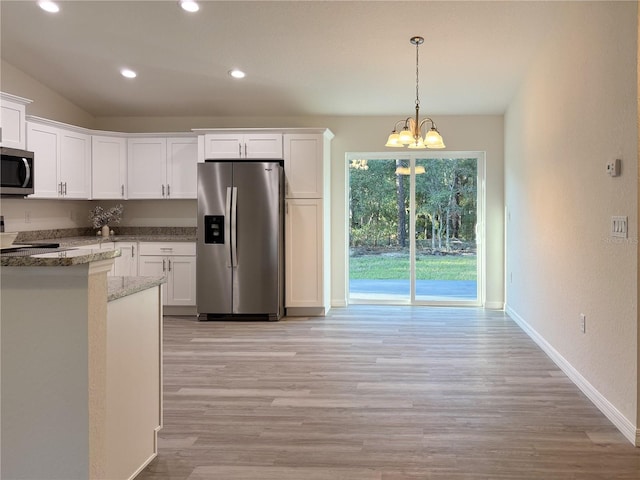 kitchen with stainless steel appliances, stone countertops, white cabinetry, and an inviting chandelier