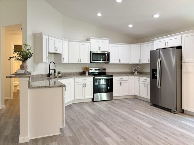 kitchen featuring appliances with stainless steel finishes, light stone counters, a peninsula, white cabinetry, and a sink