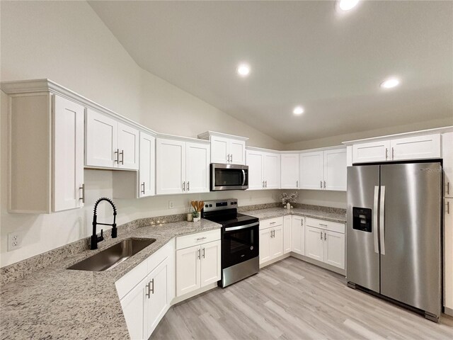 kitchen featuring light stone counters, light wood-style flooring, stainless steel appliances, a sink, and white cabinets