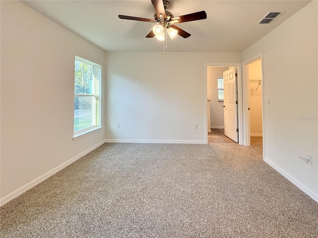 spare room featuring light carpet, a ceiling fan, visible vents, and baseboards