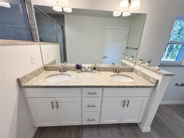 full bathroom with wood finished floors, a sink, and a shower stall