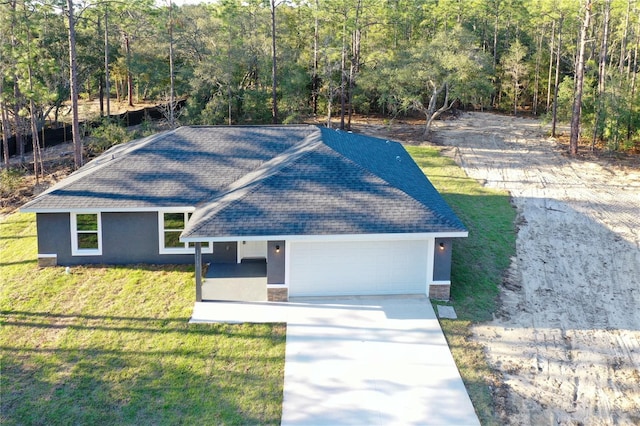 ranch-style home with a garage, a front yard, roof with shingles, and stucco siding