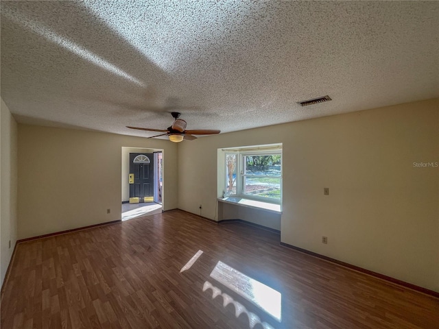 empty room featuring ceiling fan, wood finished floors, visible vents, and baseboards