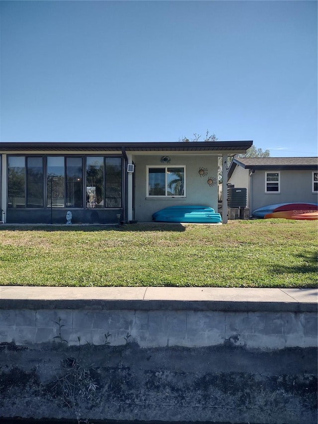 back of property featuring a yard, a sunroom, and stucco siding