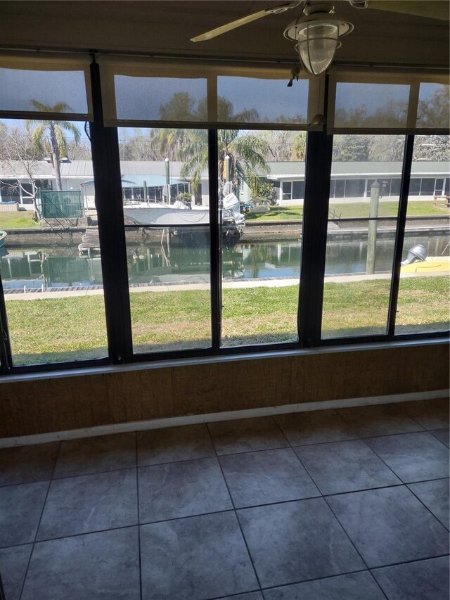 unfurnished sunroom with a water view and ceiling fan