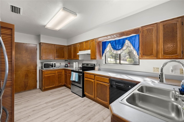 kitchen featuring under cabinet range hood, stainless steel appliances, a sink, visible vents, and light countertops