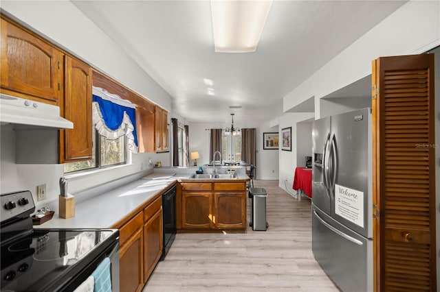 kitchen featuring light countertops, appliances with stainless steel finishes, a sink, light wood-type flooring, and a peninsula