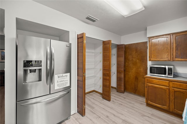 kitchen featuring brown cabinets, light countertops, visible vents, appliances with stainless steel finishes, and light wood-type flooring