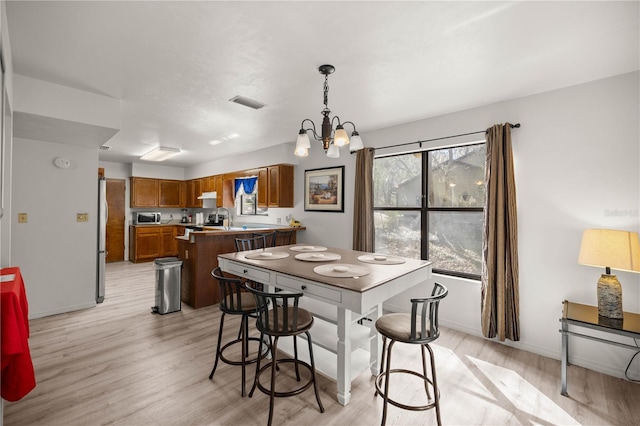 dining space with baseboards, an inviting chandelier, visible vents, and light wood-style floors