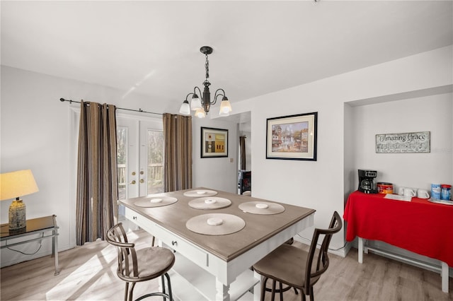 dining area with light wood finished floors and an inviting chandelier