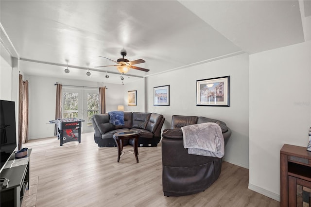 living room featuring light wood-type flooring, baseboards, and a ceiling fan