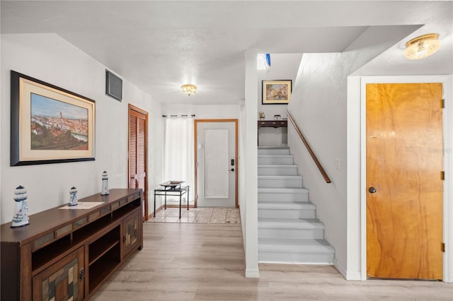 entryway with stairs, visible vents, and light wood-style floors