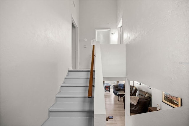 staircase with a high ceiling and wood finished floors