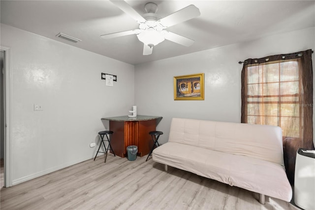 sitting room with a ceiling fan, visible vents, and wood finished floors