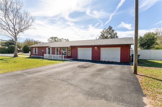 single story home with aphalt driveway, an attached garage, a front lawn, and fence