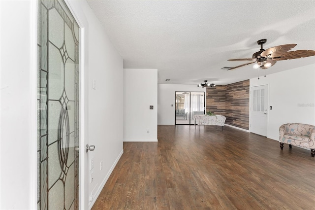 unfurnished living room with ceiling fan, baseboards, a textured ceiling, and wood finished floors