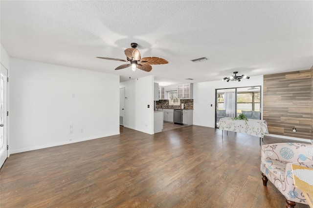 unfurnished living room featuring ceiling fan, visible vents, a textured ceiling, and dark wood finished floors