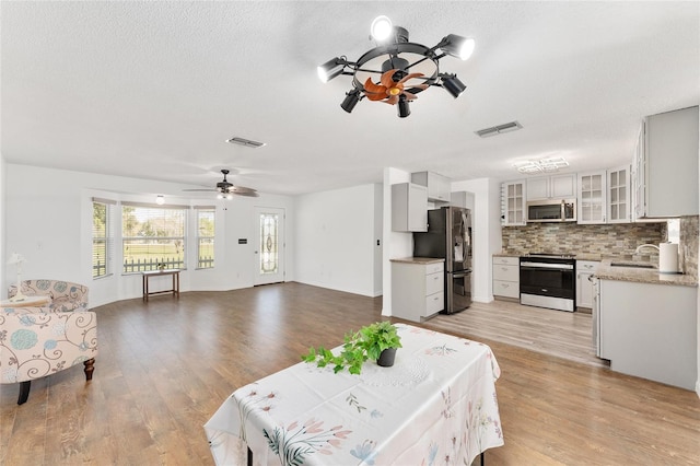 living area featuring visible vents, ceiling fan, and light wood finished floors